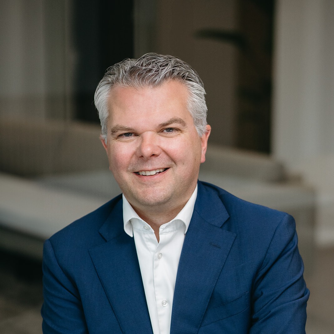 A smiling man smiling wearing a blue jacket.